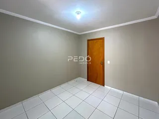 Corredor interno com piso de cerâmica branca e porta de madeira.