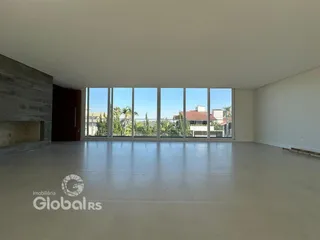 Interior de uma sala ampla com grandes janelas que dão para a paisagem.