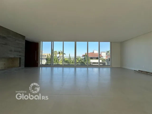 Interior de uma sala ampla com grandes janelas que dão para a paisagem.