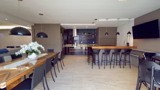 Vista de uma sala de jantar com mesa de madeira e bancos em um imóvel no Brasil.
