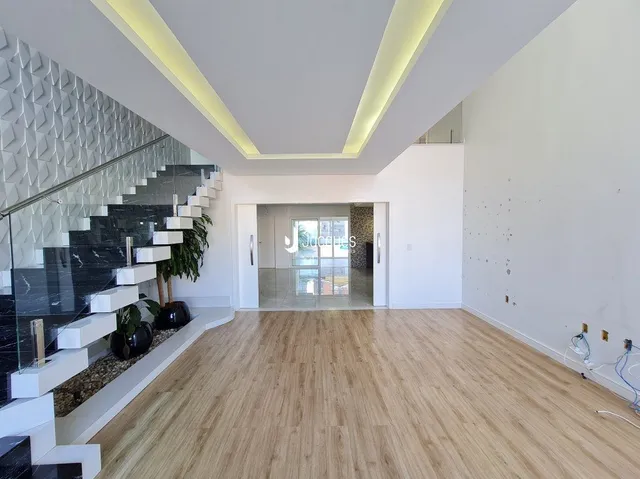 Hall de entrada com escadaria e piso de madeira clara.