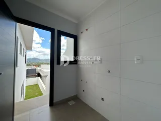 Corredor interno com paredes brancas e acesso a uma área externa.