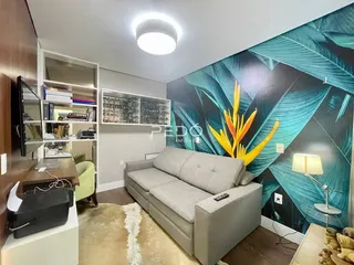 Sala de estar com sofá cinza e parede decorada em Lajeado.