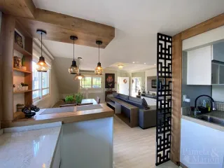 Sala de estar com ilha de cozinha e detalhes em madeira aparente.