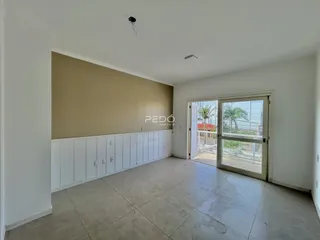 Vista interna de uma sala com piso de cerâmica e parede bege.