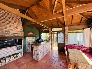 Interior de uma cozinha rústica com paredes de tijolo aparente e vigas de madeira.