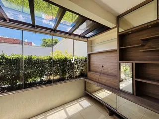 Vista interna de uma sala com grandes janelas que dão para a vegetação.