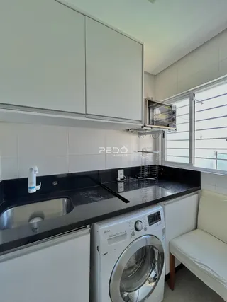 A cozinha apresenta armários brancos e bancada escura.