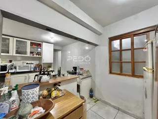 Vista interna de uma cozinha com armários brancos e piso de cerâmica.