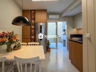 Uma sala de jantar com mesa branca e armários de madeira escura.