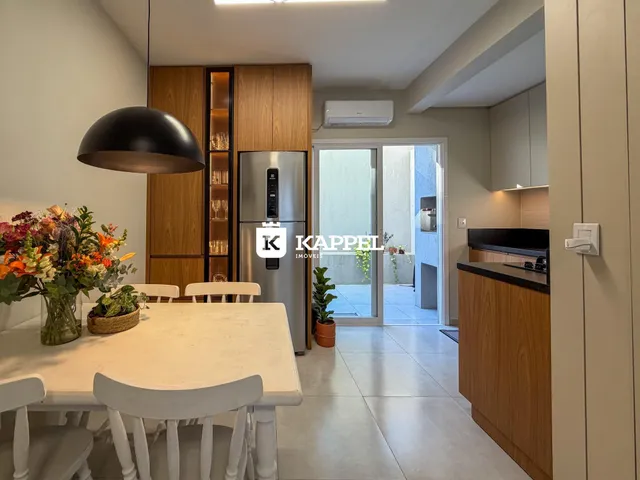 Uma sala de jantar com mesa branca e armários de madeira escura.