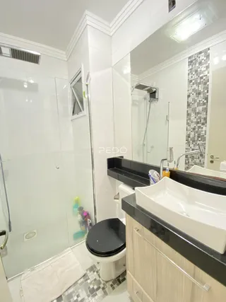 Banheiro moderno com box de vidro e bancada dupla.