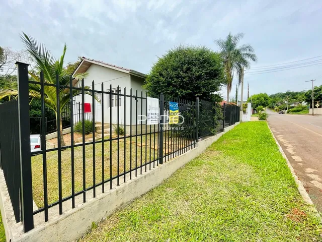 Vista da fachada de uma residência com cerca e jardim.