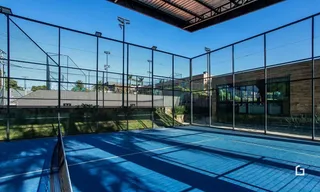 Uma quadra esportiva externa cercada por grade de arame.