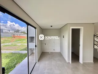 Vista interna de um corredor com piso de cerâmica e vista para uma área gramada.
