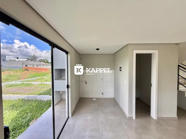 Vista interna de um corredor com piso de cerâmica e vista para uma área gramada.