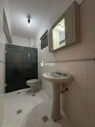 Foto de um banheiro com revestimento cerâmico claro e azulejos brancos.