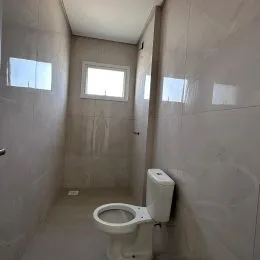 Foto interna de um banheiro com paredes brancas e vaso sanitário.