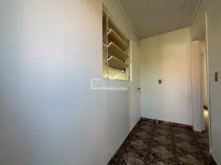 Vista do corredor interno de uma residência com piso de cerâmica.
