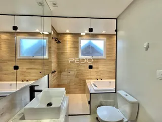 Interior de um banheiro com revestimento de madeira e louças brancas.