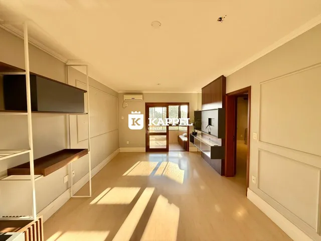 Uma sala ampla com piso de madeira clara e estantes.