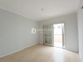 Ambiente interno de uma sala com piso de madeira clara e porta de vidro.