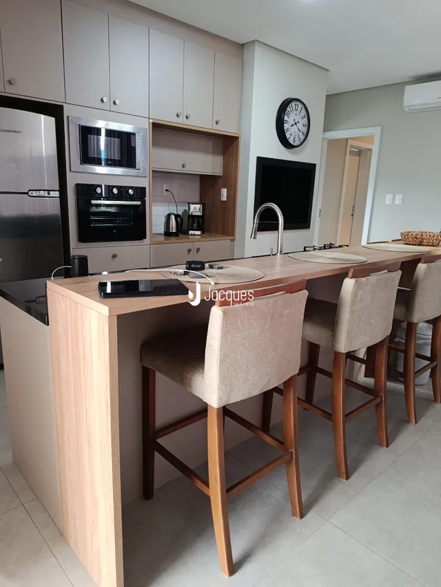 Cozinha moderna com ilha e armários de madeira clara.