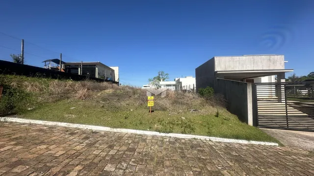 Vista externa de uma propriedade com gramado e estruturas ao fundo.