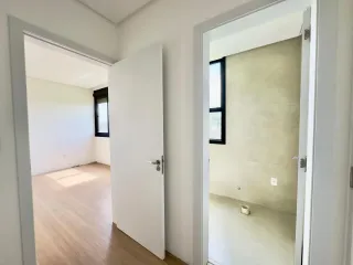 Hall de entrada com piso de madeira e parede branca.