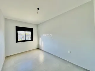Ambiente interno de uma sala com piso de cerâmica e parede branca.