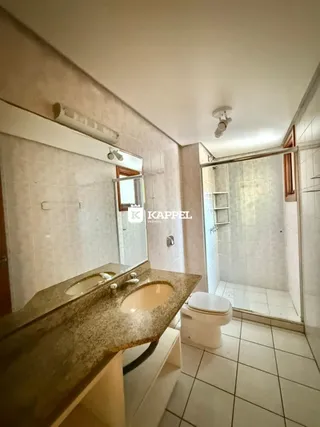 Foto de um banheiro com bancada e box de vidro.
