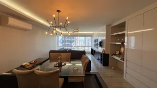 Sala de estar com mesa de jantar e grandes janelas.