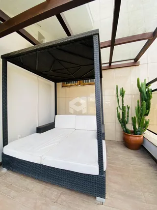 Área externa com cama de madeira e cactos.