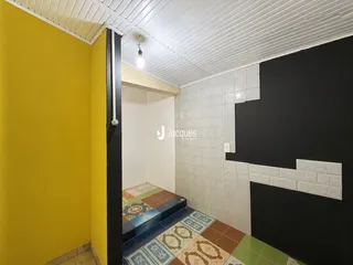 Uma passagem interna com paredes amarelas e escuras e piso de azulejos.