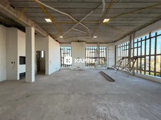 Foto de um espaço interno com estrutura aparente e grandes janelas.