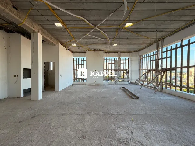 Foto de um espaço interno com estrutura aparente e grandes janelas.