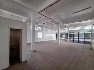 Vista interna de um espaço amplo com paredes brancas e piso de cerâmica.