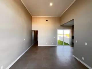 Vista de um corredor interno com paredes claras e piso escuro.