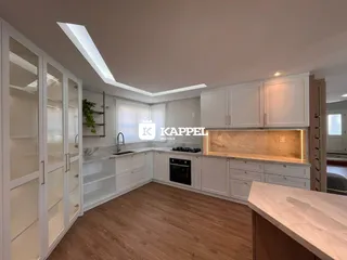 Cozinha moderna com armários brancos e piso de madeira clara.