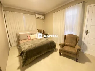 Quarto com cama e poltrona em um ambiente claro com cortinas brancas.