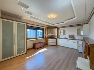 Sala de estar com piso de madeira e grandes janelas.
