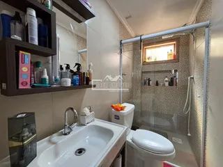 Foto de um banheiro com box de vidro e revestimento cerâmico.