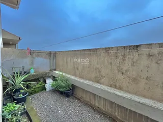 A foto mostra uma parede externa de um imóvel em Lajeado, Brasil, com um muro de concreto e plantas.