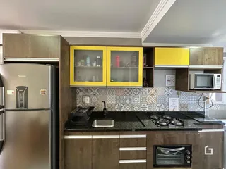 Cozinha com armários de madeira e bancada escura.