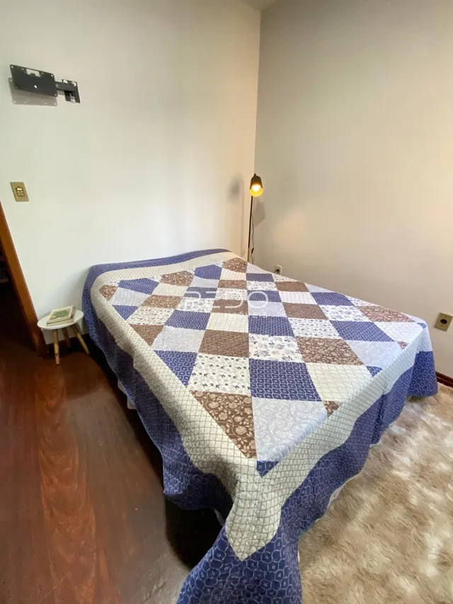 Quarto com cama coberta por um edredom estampado.