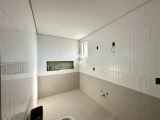 Interior de um ambiente com revestimento cerâmico branco e piso claro.