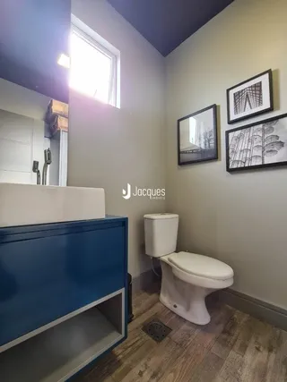 Foto de um banheiro interno com vaso sanitário branco e piso de madeira clara.