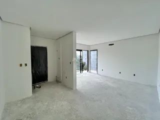 Interior de um espaço com paredes brancas e piso de concreto.