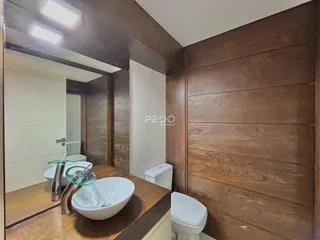 Interior de um ambiente com revestimento de madeira e reflexo de um banheiro.