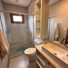 Foto de um banheiro com box de vidro e revestimento cerâmico.